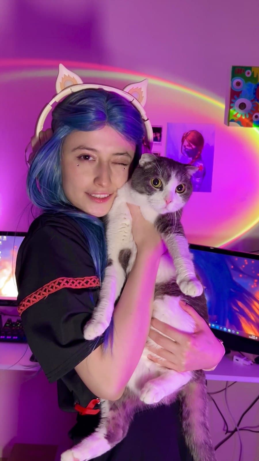 Faina holding her cat in a pink gaming room